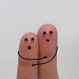 Zwei mit Gesichtern und Armen bemalte Finger halten sich aneinander fest und haben Angst vorm weißen Blatt