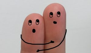 Mit Gesichtern und Armen bemalte Finger halten sich ängstlich aneinander fest
